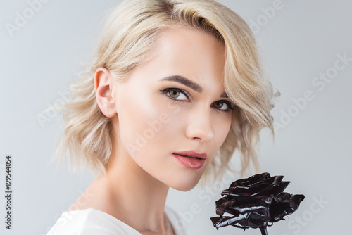 portrait of attractive blonde girl with black rose, isolated on grey