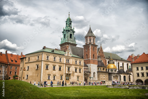Krakow, Poland - June 04, 2017: Wawel cathedral with chapels on green hill. Tourists at catholic church on cloudy sky. Architecture and design. Travelling, vacation and wanderlust