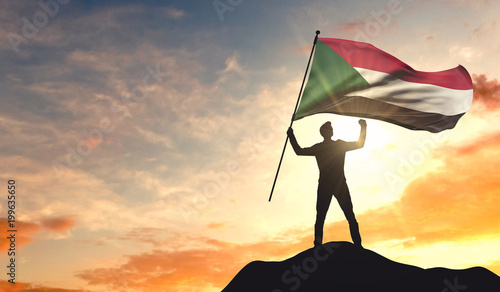 Sudan flag being waved by a man celebrating success at the top of a mountain. 3D Rendering