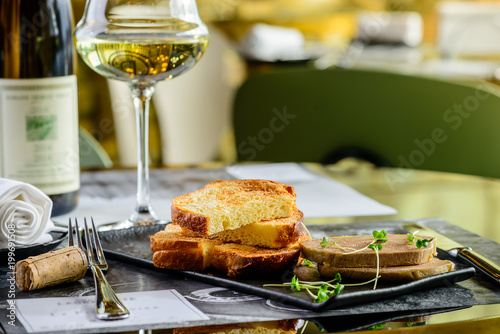 Tasty foie Gras with toasts and glass of white wine at a restaurant