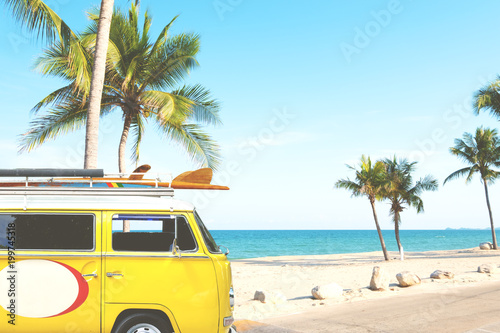 vintage car parked on the tropical beach (seaside) with a surfboard on the roof - Leisure trip in the summer. retro color effect