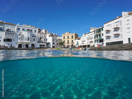 Waterfront village of Cadaques with a small beach and a sandy seabed underwater, split view above and below water surface, Mediterranean sea, Costa Brava, Spain