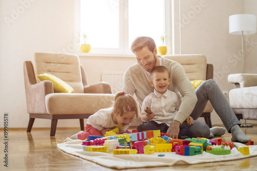 Father with children playing together with block toys in living room