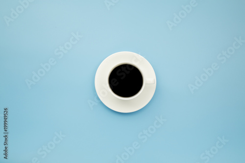 Black coffee in white cup on blue blackground pastel style copyspace flatlay.