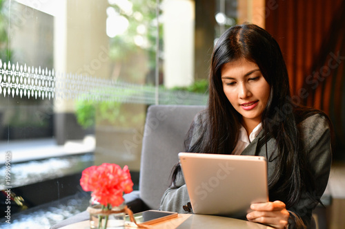 Business Concept.Young Asian businesswoman is working happily.Young businesswoman working in a cafe.Young businesswoman is relaxation in a coffee shop.