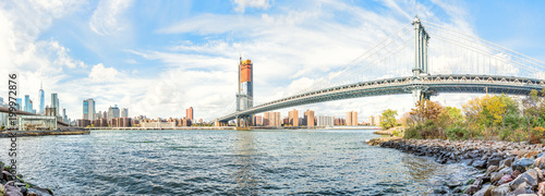 Panorama of east river with view of NYC New York City cityscape skyline, Manhattan and Brooklyn bridge by beach