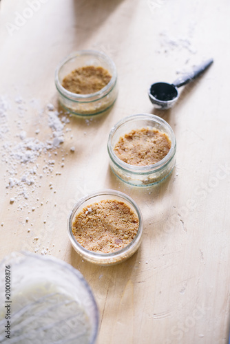 Preparation of a cheesecake on jar without baking it, biscuit mixed with butter are pressed in glass container