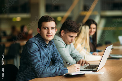 Group of college students studying in the school library, a girl and a boy are using a laptop and connecting to internet