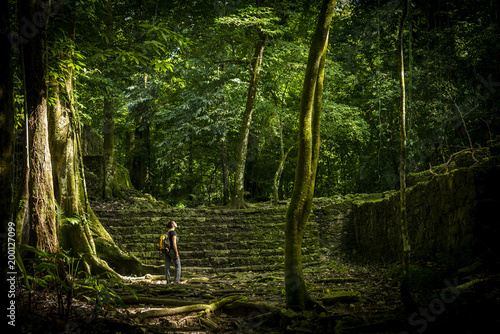 Woman stands in think jungle with a backpack on for female solo adventure travel concept