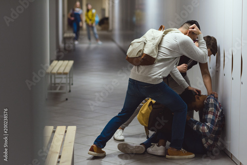 frightened african american schoolboy being bullied in school corridor