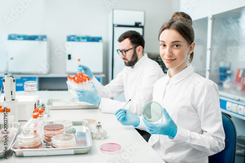 Couple of medics in uniform making bacteriological tests sitting in the modern laboratory