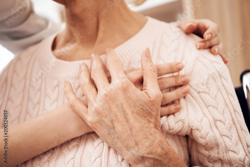 Close up. Girl is caring for elderly woman at home. Girl is embracing woman.