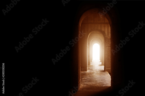 Silhouette of the cross at the end of tunnel with ray of sunlight behind