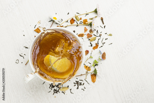 cup of tea on white table with lemon slice splashing