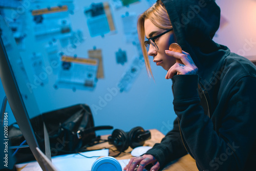 side view of serious young female hacker holding bitcoin