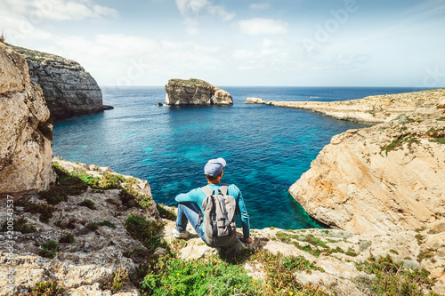 Backpacker traveler relax on the rocky coast of blue sea lagoon