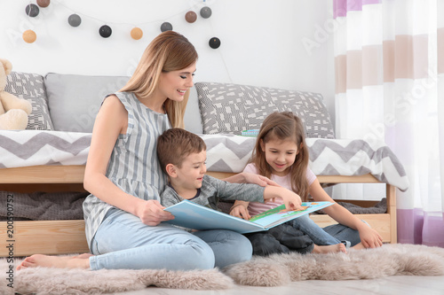 Nanny reading book to little children at home