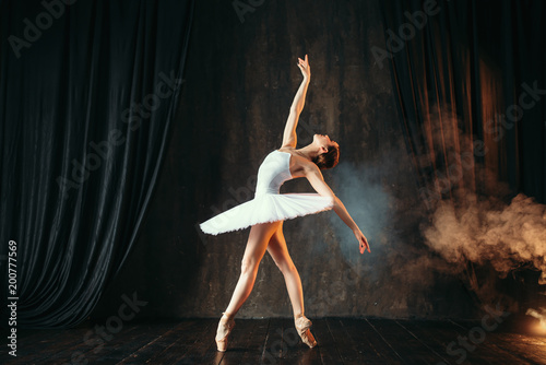 Balerina w białej sukni tańczy w klasie baletu