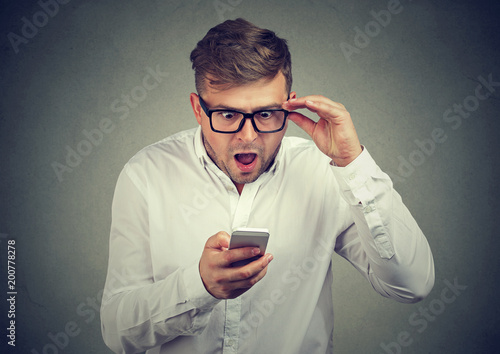 Shocked man in glasses watching phone