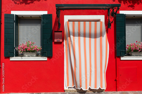 The facade of a yellow-painted house with beautiful Mediterranean-style shutters