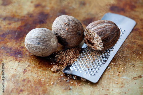 Making nutmeg powder process. Nuts silver grater. Kitchen still life photo. Shallow depth of field, aged brown rusty background. Selective focus.