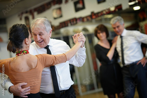 Senior man dancing with dance teacher during group class