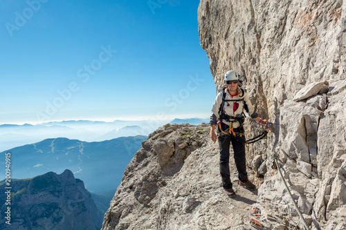 Happy female mountaineer climbing via ferrata.
