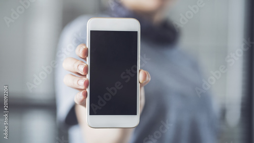 Woman holding and showing mobile phone 