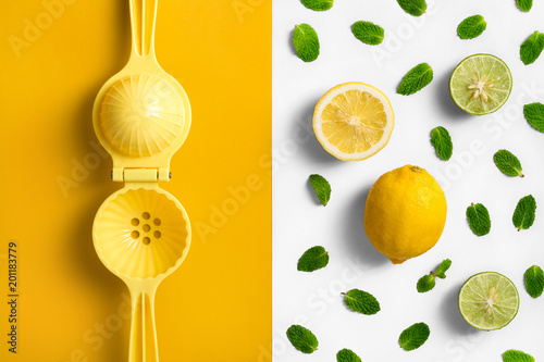 Lemon juicer. hand press, on split colored background with lemon lime and mint leaves.