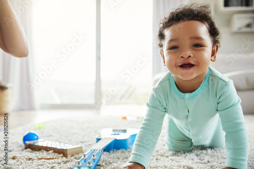 Happy mixed race toddler boy crawling in sitting room