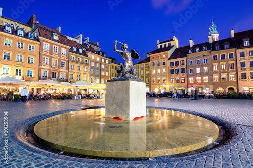 Night view of the bronze statue of Mermaid on the Old Town Market Square of Warsaw, surrounded by colorful old houses, Poland.