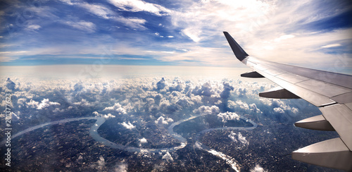 Concepto de viaje en avión .Volando sobre la ciudad hacia el destino. Paisaje al atardecer sobre las nubes.