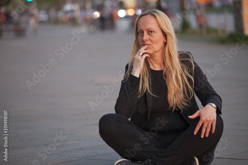 Mujer de negocios pensativa con gesto de preocupación sentada en mitad de la acera de la calle.. Algo está pasando en su entorno laboral.