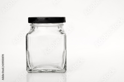 Square empty glass jar with black lid.