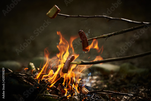 Kiełbasa pieczona nad ogniskiem w płomieniach ognia. 