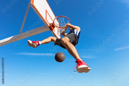 Slam Dunk. Side view of young basketball player making slam dunk