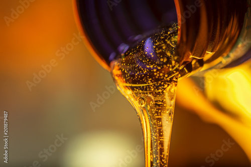 Liquid stream of motorcycle motor oil flows from the neck of the bottle close-up.