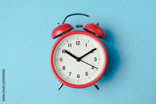 Red vintage alarm clock on light blue color background