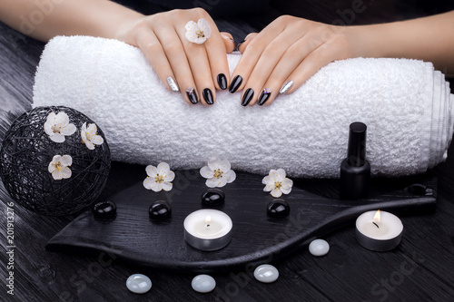 beautiful black manicure with apricot flower and towel on the wooden table. spa