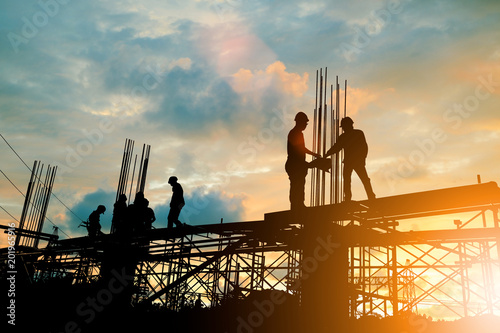 Silhouette of engineer and construction team working at site over blurred background sunset pastel for industry background with Light fair.