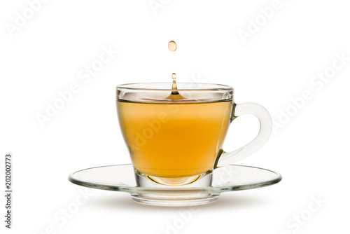tea in glass cup with drop splashing, on white background.