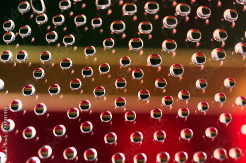 Drops of water on the glass, in which the background of the colored strips is reflected.