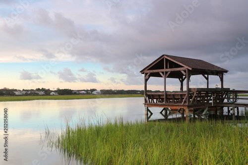 Cloudy evening landscape with beautiful colors sky reflected in a Pawleys Island bay water with private wooden dock with observation and fishing point. Myrtle Beach area, South Carolina, USA.