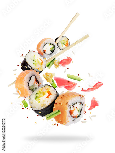 Different fresh sushi rolls with chopsticks frozen in the air on white background