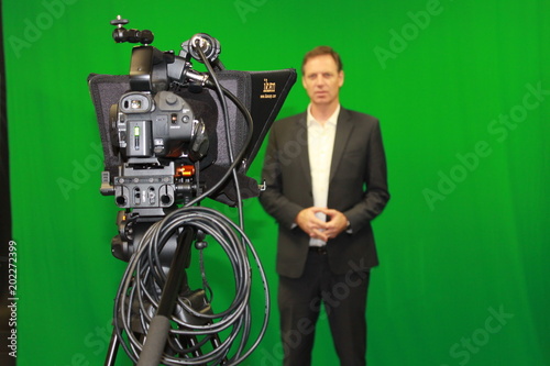 Man reading autocue teleprompter against green screen