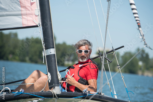 mature man enjoying sailing on a hobie cat boat