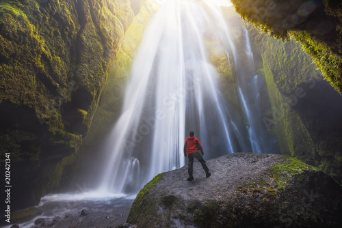 Man looking at the Gljufrabui Waterfall inside a cave in Iceland