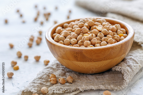 Chickpeas in wooden bowl on a linen cloth.