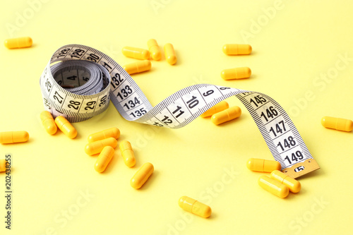 centimeter tape and pills on a colored background with space for text. concept of losing weight, diet, fat burning, healthy eating. minimalism. 