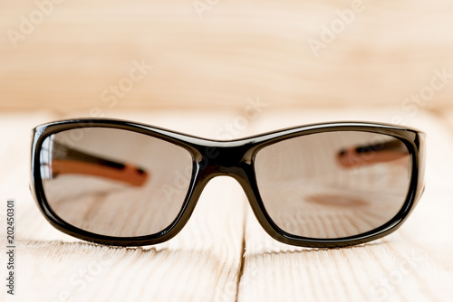 sunglasses with brown polarizing glasses lie on a wooden surface, close-up photos taken